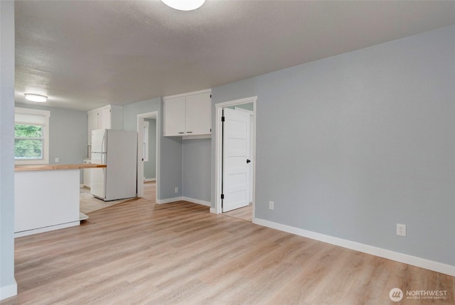 interior space featuring baseboards and light wood finished floors