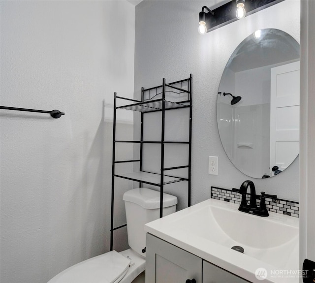 bathroom with vanity, a textured wall, backsplash, and toilet