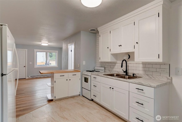 kitchen with a peninsula, white appliances, light countertops, a baseboard heating unit, and a sink