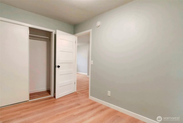 unfurnished bedroom with light wood-style floors, baseboards, and a closet