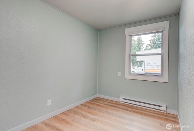 unfurnished room with light wood-style floors, baseboards, and a baseboard heating unit