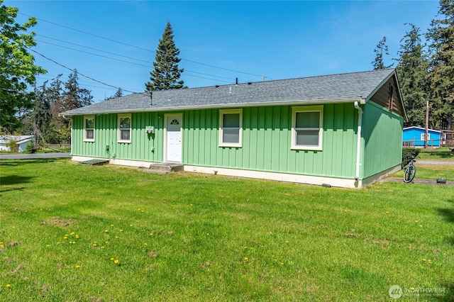 view of front of property featuring board and batten siding, roof with shingles, and a front yard