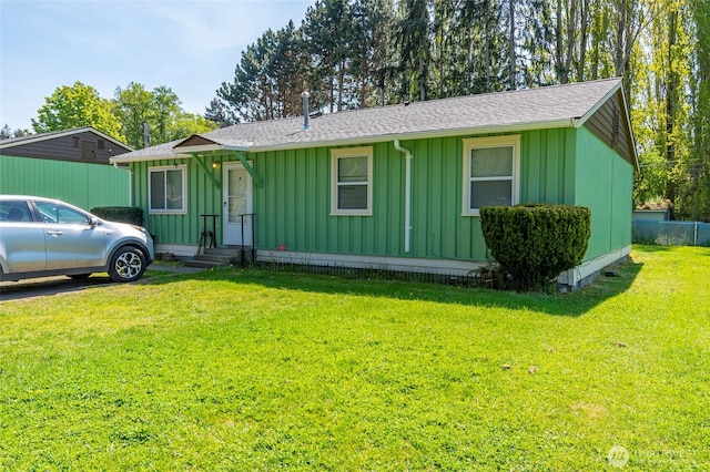 view of front of home featuring roof with shingles, board and batten siding, and a front lawn