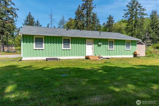 view of front of house with a shingled roof, board and batten siding, and a front yard