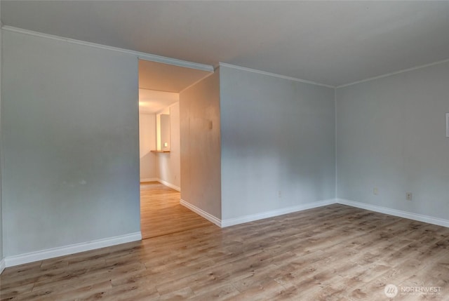 empty room with crown molding, baseboards, and wood finished floors