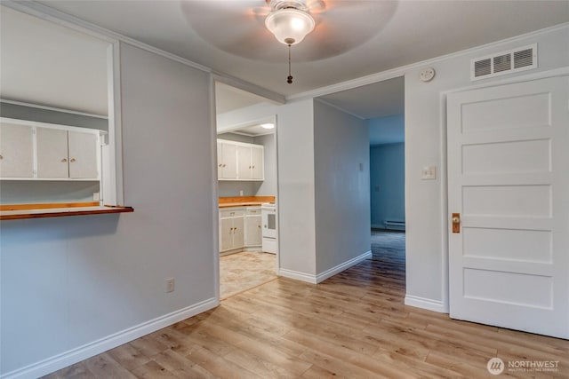 unfurnished dining area with a ceiling fan, visible vents, baseboards, ornamental molding, and light wood-style flooring