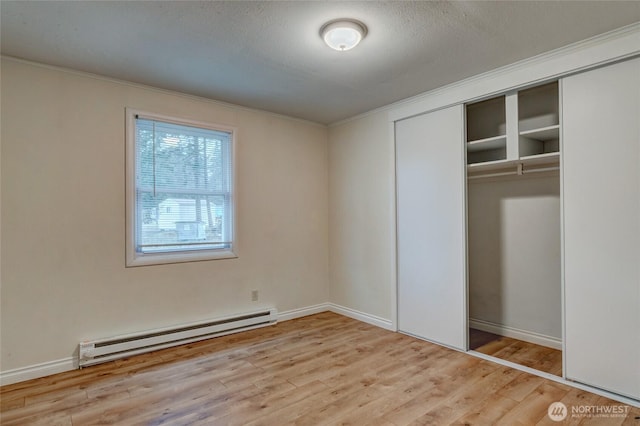 unfurnished bedroom with crown molding, baseboard heating, a closet, and wood finished floors