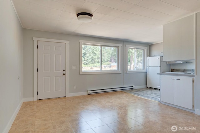 interior space featuring light tile patterned floors, baseboards, a sink, and baseboard heating