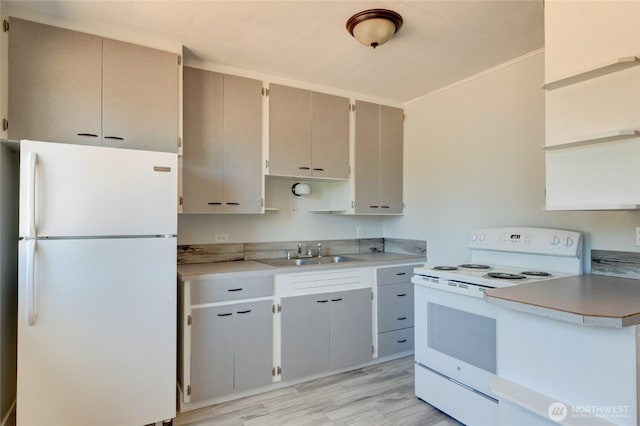 kitchen with a sink, light countertops, light wood-type flooring, and white appliances