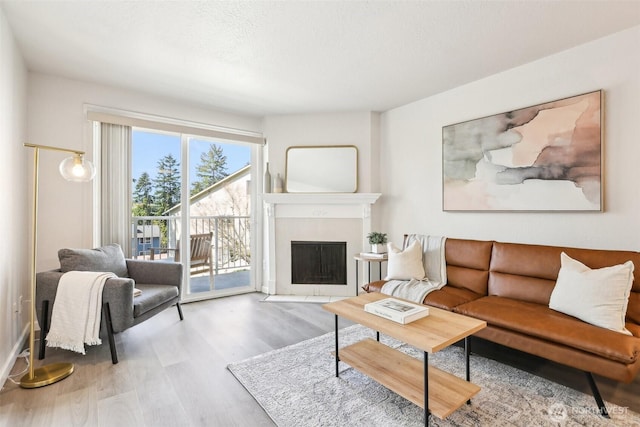 living area featuring a fireplace with flush hearth, wood finished floors, and a textured ceiling
