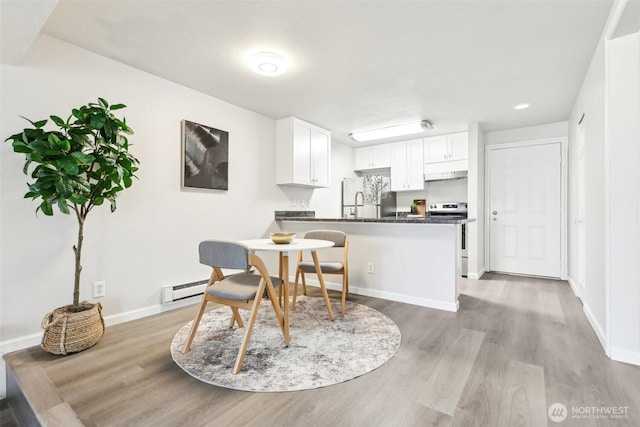 dining space with light wood-style flooring, baseboards, and baseboard heating