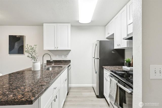 kitchen featuring a sink, stainless steel range with electric cooktop, light wood-type flooring, dishwasher, and a peninsula