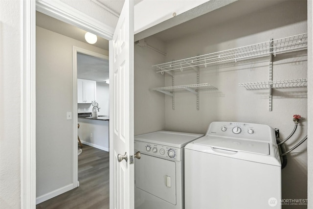 washroom featuring baseboards, laundry area, washer and clothes dryer, and dark wood-type flooring
