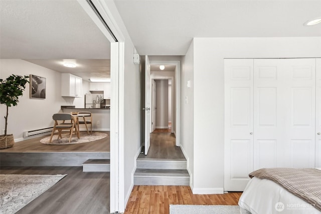 bedroom with light wood-type flooring, baseboards, freestanding refrigerator, and a closet