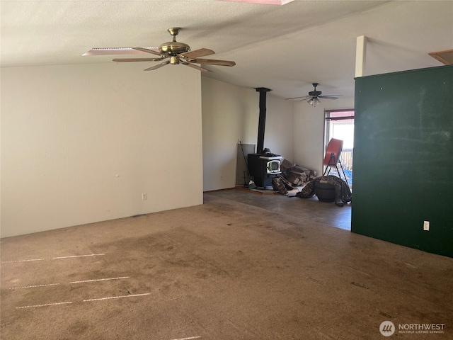 carpeted living room featuring a ceiling fan, vaulted ceiling, and a wood stove
