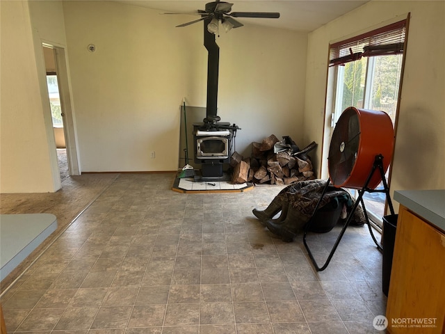 living room featuring a wood stove and ceiling fan