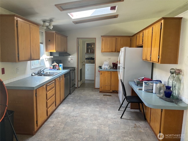 kitchen with brown cabinetry, a sink, and vaulted ceiling with skylight