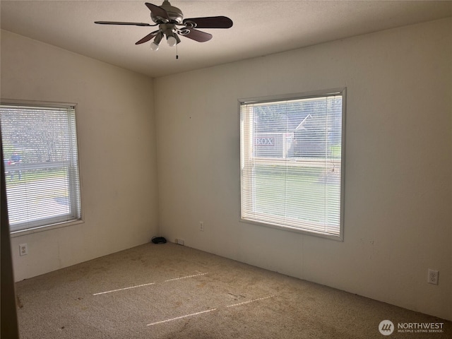 carpeted spare room featuring ceiling fan