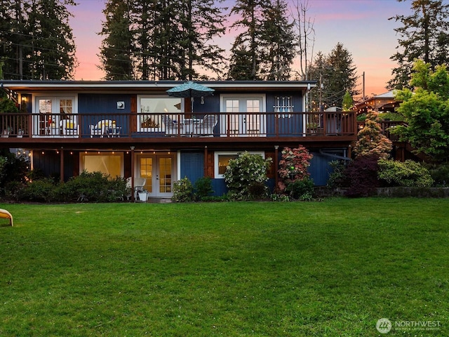 back of house with french doors, a wooden deck, and a lawn