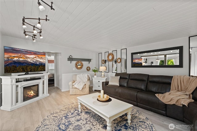 living area with wooden ceiling, wood finished floors, and a glass covered fireplace