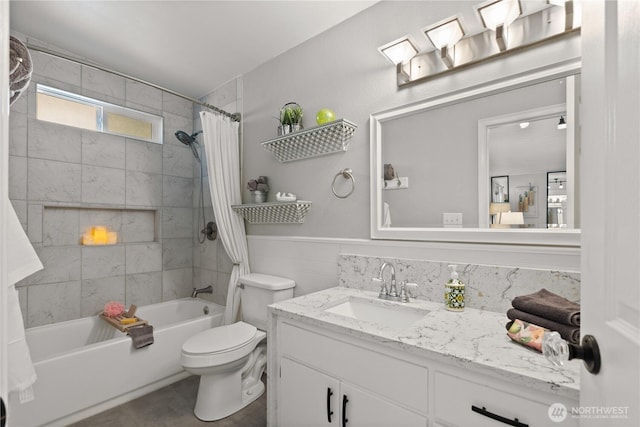 full bathroom with shower / tub combo with curtain, vanity, toilet, wainscoting, and tile walls
