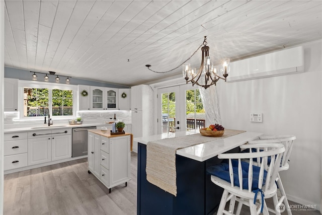 kitchen with a sink, stainless steel dishwasher, wood ceiling, plenty of natural light, and glass insert cabinets