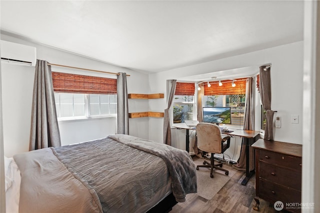 bedroom with a wall mounted AC, wood finished floors, and a desk