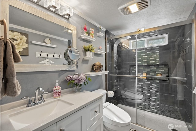 full bath with toilet, vanity, a textured ceiling, a stall shower, and ornamental molding