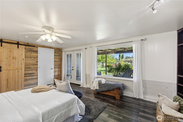 bedroom featuring wood walls, french doors, a barn door, wood finished floors, and access to exterior
