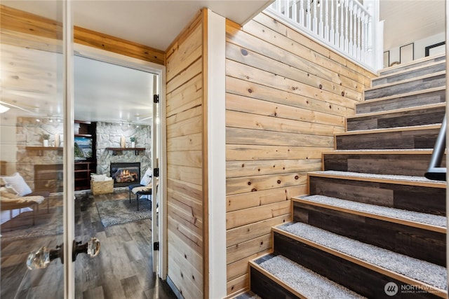 stairway with wood walls, wood finished floors, and a fireplace
