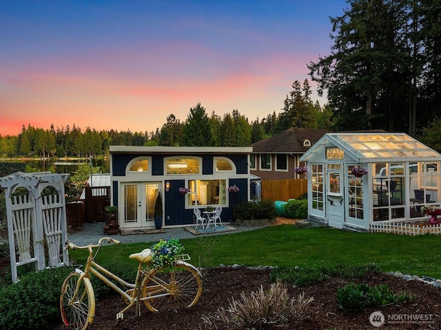 back of house at dusk with an outbuilding and a greenhouse