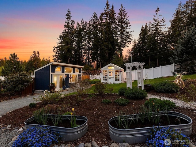 yard at dusk featuring an outdoor structure and a vegetable garden