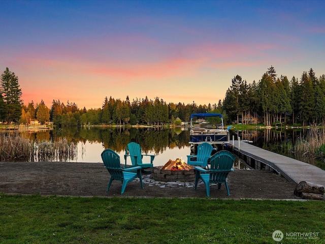 dock with a water view, a fire pit, and a lawn
