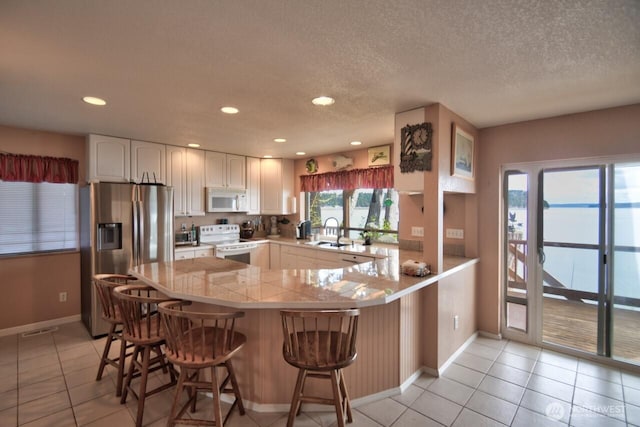 kitchen with white appliances, baseboards, a sink, and light tile patterned flooring