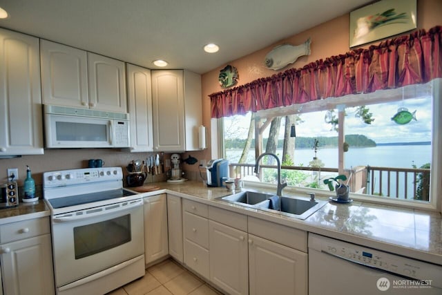 kitchen with white cabinetry, light tile patterned floors, a sink, and white appliances