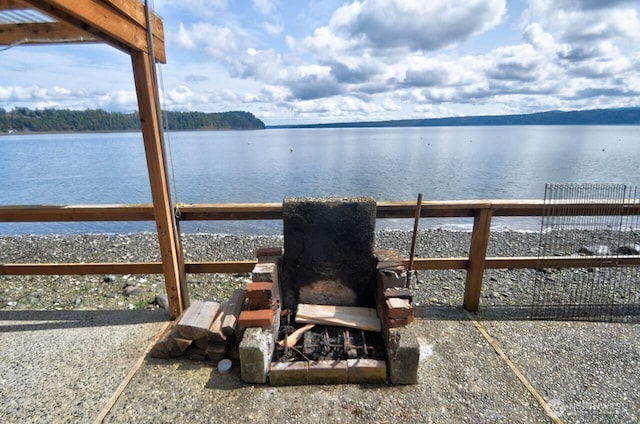 view of patio with a water view and fence