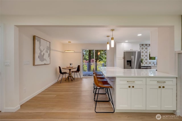 19010 12th Ave NE, Shoreline, WA 98155 - kitchen with stainless steel refrigerator with ice dispenser, white cabinets, light countertops, light wood-style flooring, and hanging light fixtures