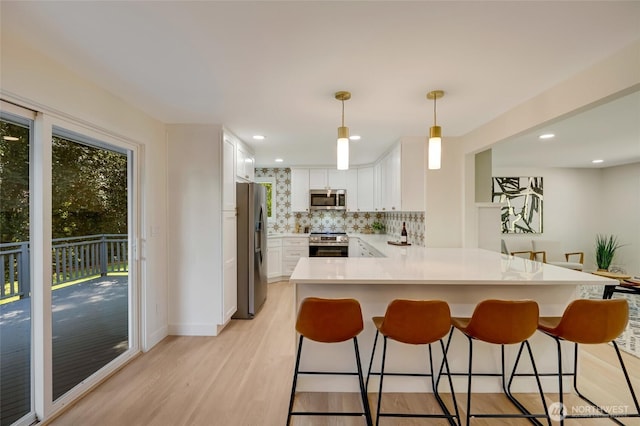 19010 12th Ave NE, Shoreline, WA 98155 - kitchen with appliances with stainless steel finishes, a peninsula, light wood-style floors, decorative backsplash, and white cabinets