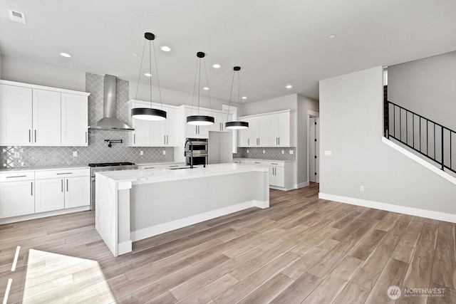 1436 238th St SE, Bothell, WA 98021 - kitchen with wall chimney range hood, appliances with stainless steel finishes, tasteful backsplash, white cabinets, and light wood-style floors