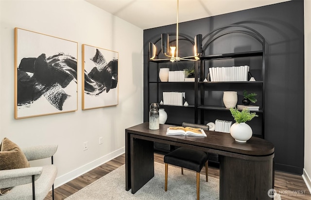 office area with baseboards, a notable chandelier, and wood finished floors