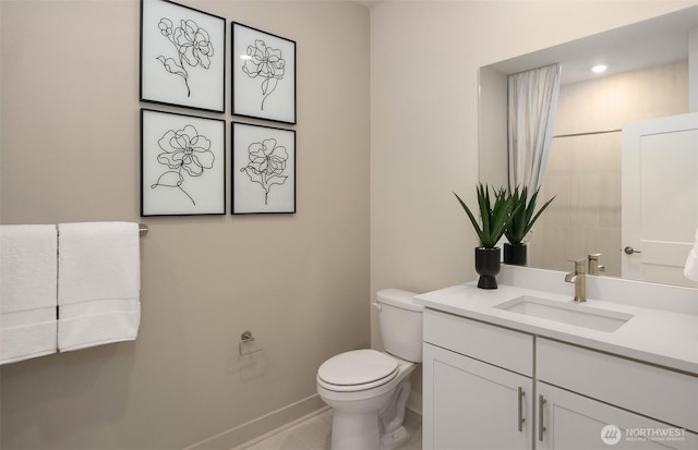 bathroom with toilet, vanity, and baseboards