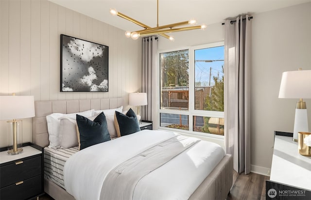 bedroom with wood finished floors, a notable chandelier, and baseboards