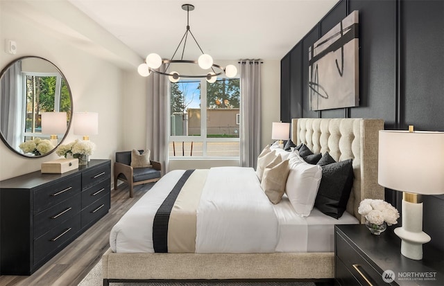 bedroom with multiple windows, an inviting chandelier, and wood finished floors