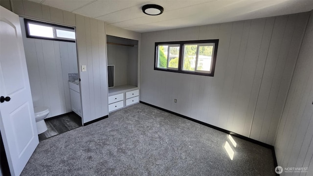 411 W Grove St Unit B, Shelton, WA 98584 - unfurnished bedroom with dark colored carpet, wooden walls, and multiple windows