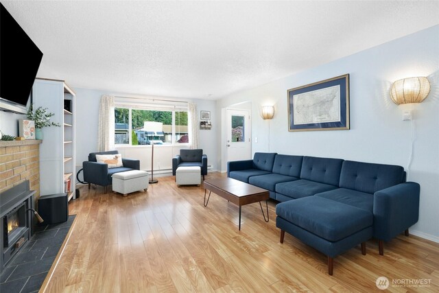 living room featuring light wood-type flooring, a baseboard radiator, a textured ceiling, and baseboards