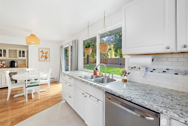 kitchen featuring a sink, dishwasher, white cabinetry, light tile patterned floors, and tasteful backsplash