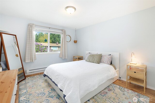 bedroom with baseboards, wood finished floors, and a baseboard radiator