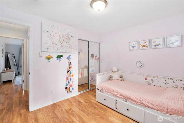 bedroom with light wood finished floors and a closet