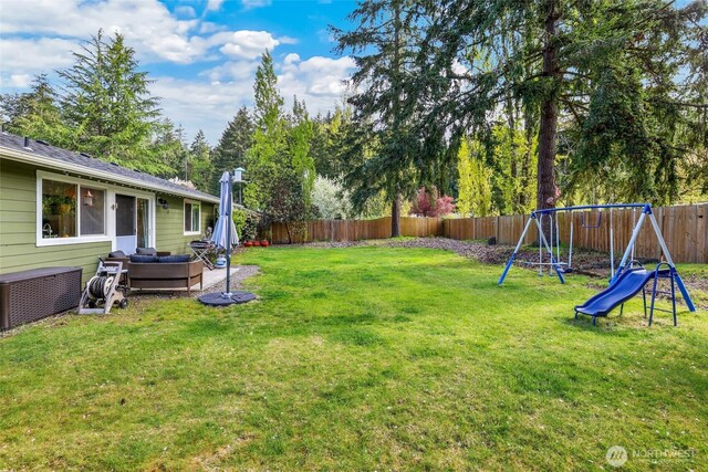 view of yard featuring a playground, an outdoor living space, and a fenced backyard