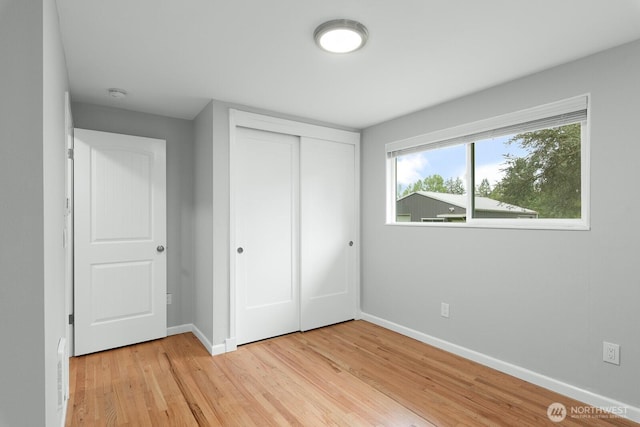 unfurnished bedroom featuring baseboards, light wood-type flooring, and a closet